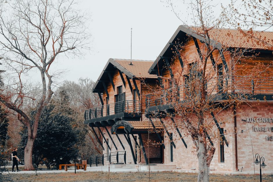 A charming wooden house surrounded by autumn trees in a serene park setting.
