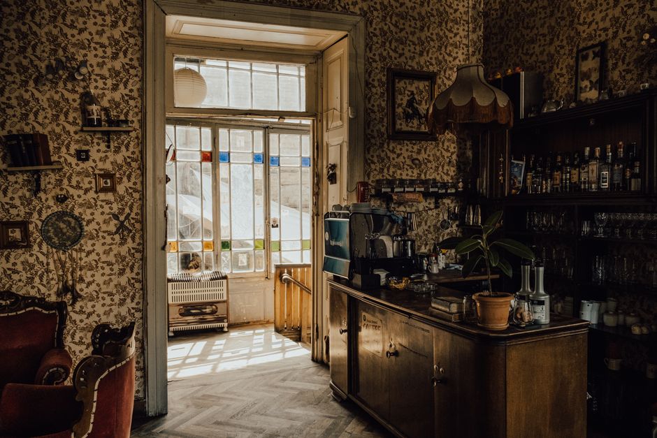 Warm, rustic interior with vintage decor, bar, and sunlight streaming through stained glass.