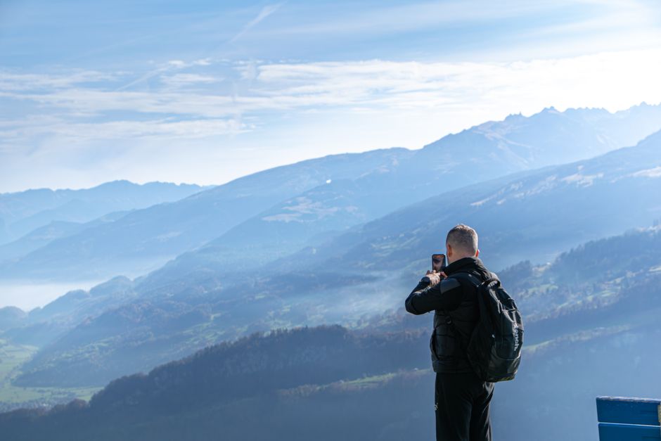 A traveler takes photos of the scenic Swiss Alps in Walenstadt with a clear blue sky.