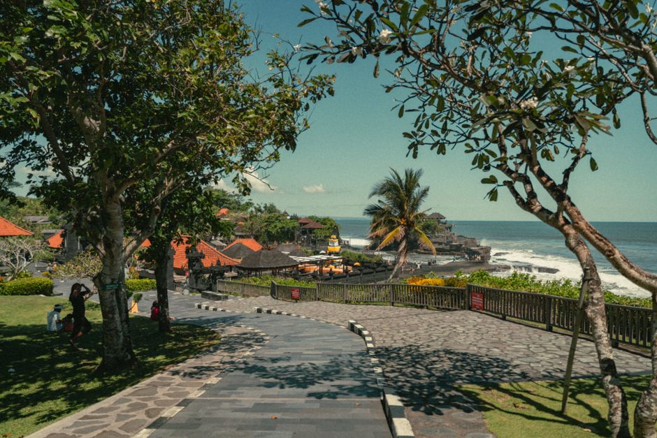 A picturesque view of Tanah Lot Temple surrounded by trees and ocean in Bali, Indonesia.