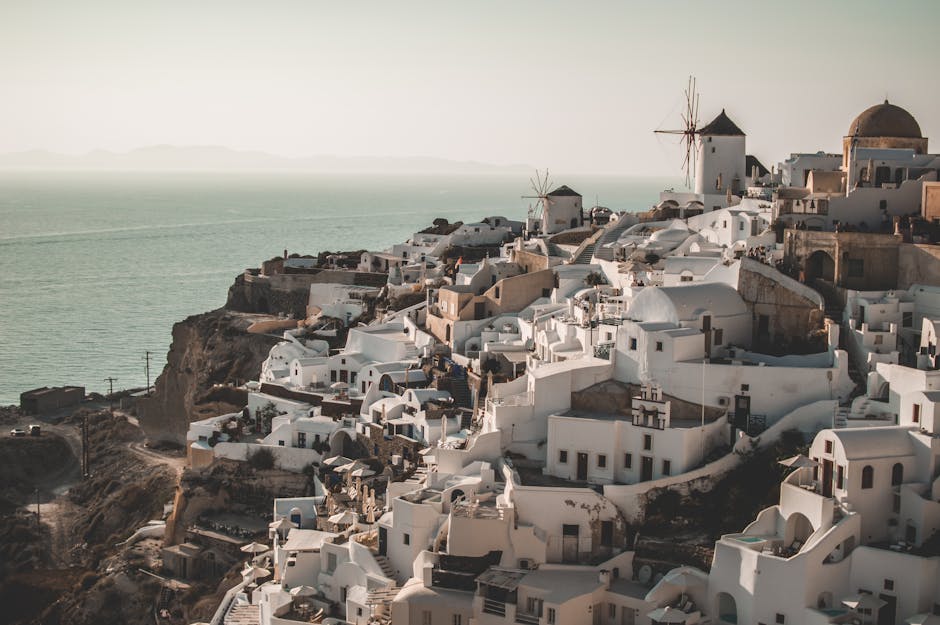 Breathtaking view of Santorini's Oia with iconic whitewashed buildings and windmills under a serene sky.