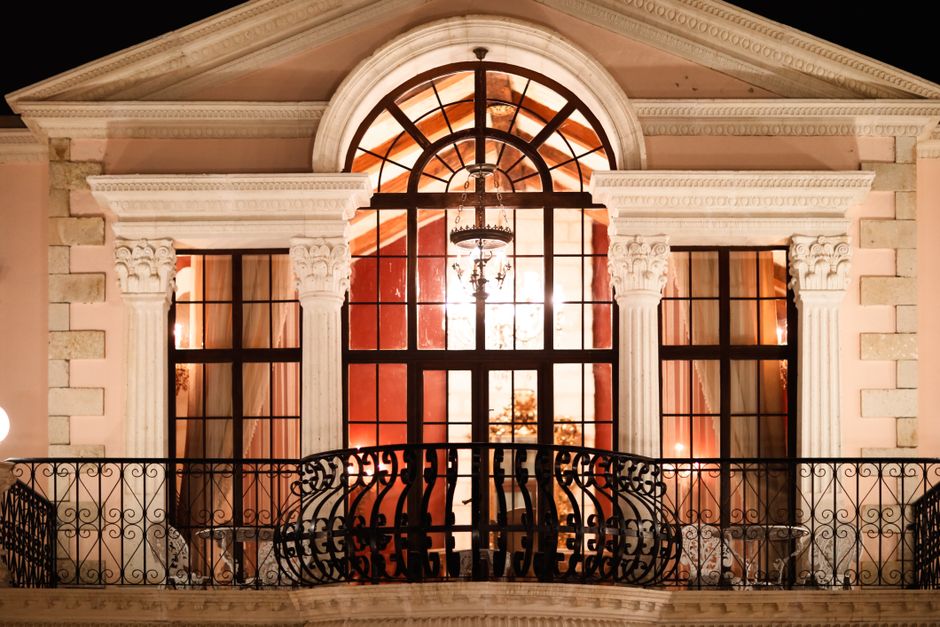 An illuminated neoclassical balcony at night showcasing ornate architecture and warm lighting.