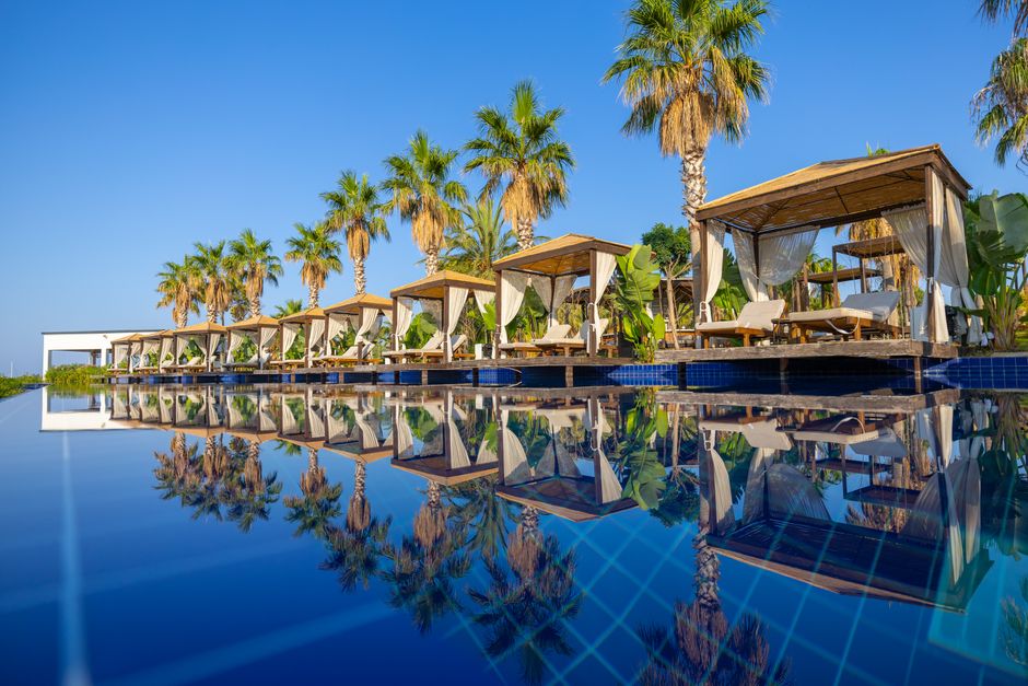 Relax by the cabana and palm trees by the pool on a sunny day in Didim, Türkiye.