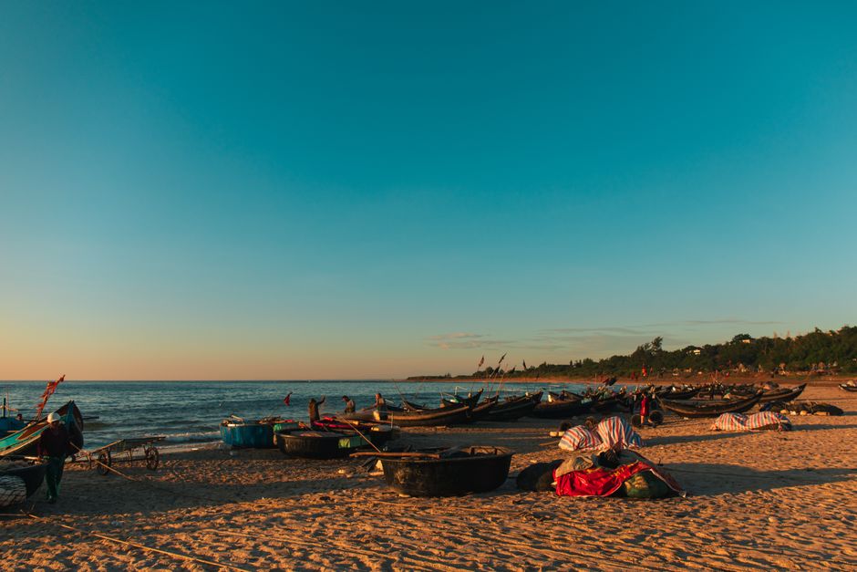 Serene Quảng Trị beach with traditional fishing boats at sunset, capturing local culture and beauty.