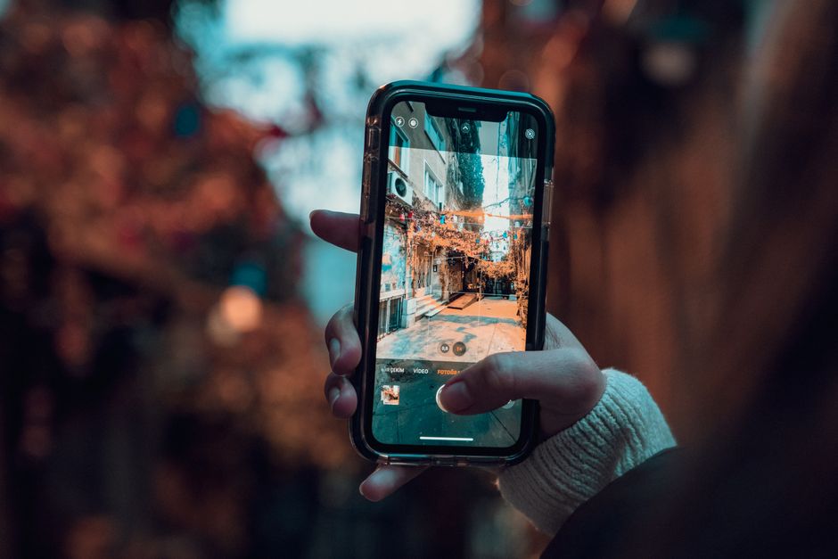 A hand holding a smartphone capturing a street scene in İstanbul.