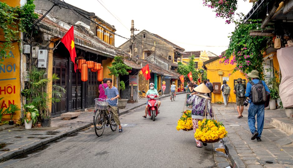 Colorful street in Hoi An, Vietnam featuring pedestrians, lanterns, and traditional architecture.
