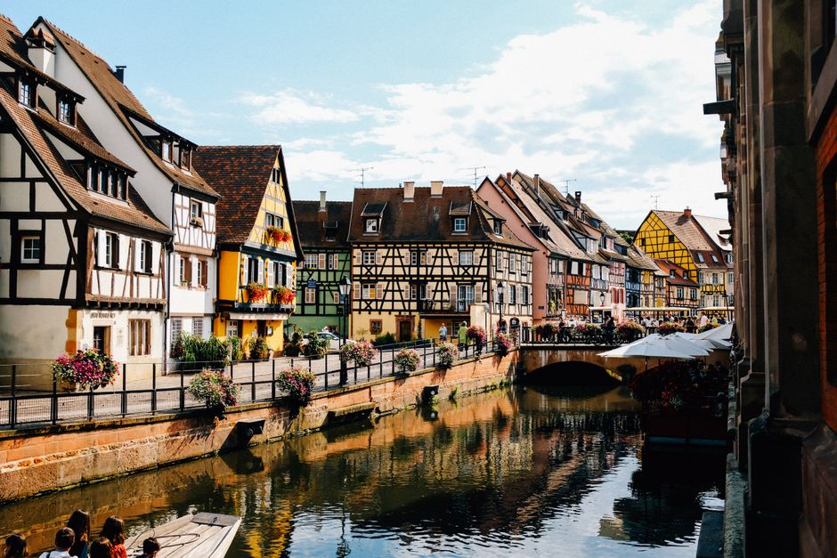 Exterior of old traditional half timbered houses located on embankment near canal flowing in Colmar on sunny day