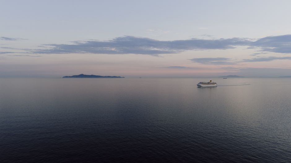 A serene view of a cruise ship sailing at dusk near Sounion, Greece.