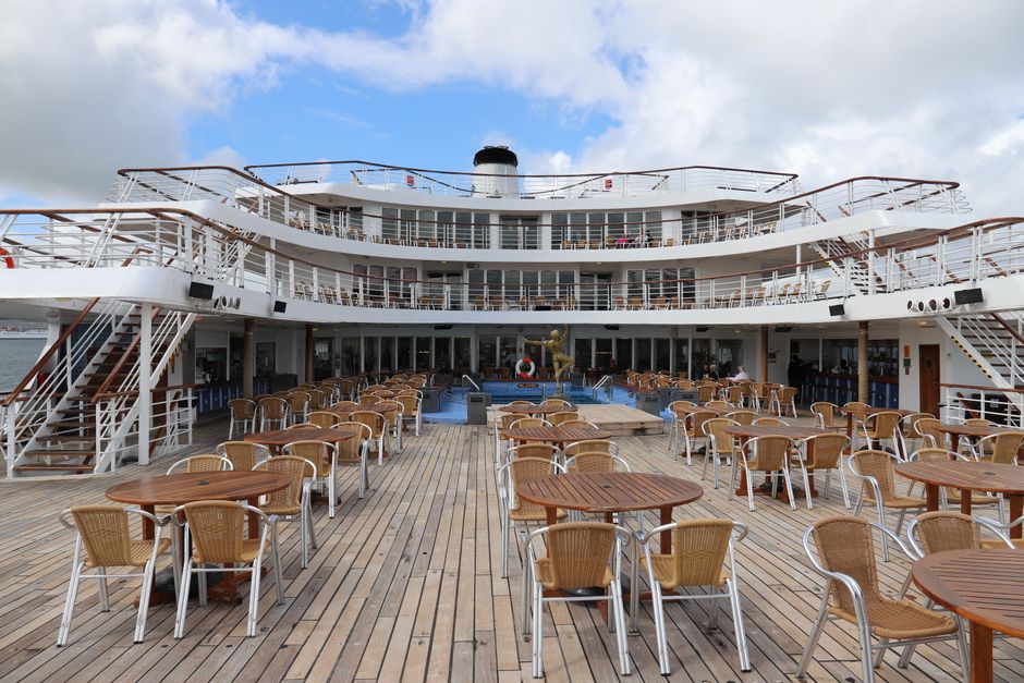 Empty cruise ship deck with tables and chairs, ideal for leisure travel.