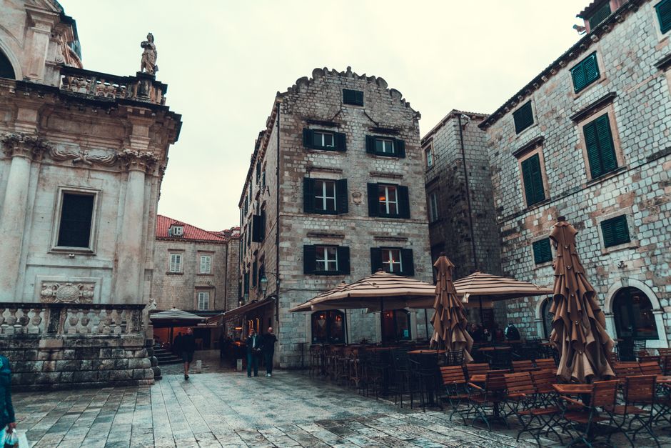 Charming European street with historic stone buildings, a cathedral, and outdoor cafe seating at dusk.
