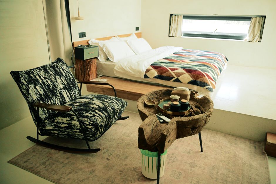 Inviting minimalist bedroom featuring a cozy bed, stylish rocking chair, and unique wooden table.