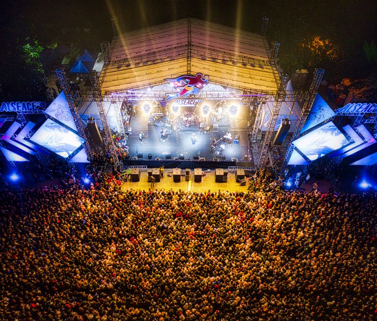 A lively aerial shot showcasing a large concert crowd at a bustling music festival.