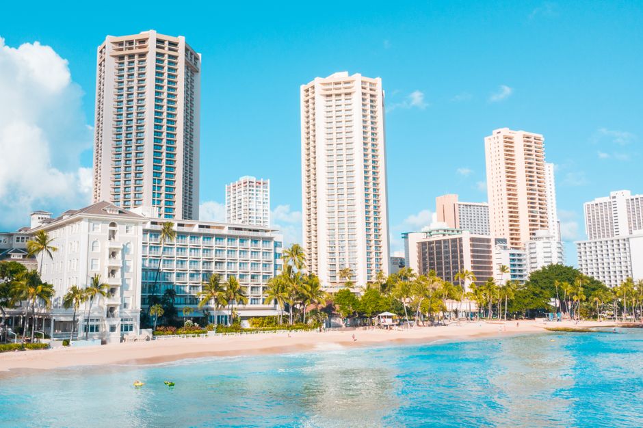 Idyllic beachfront with towering modern buildings and palm trees, perfect vacation setting.