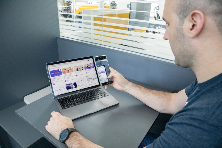 A man multitasking with a laptop and smartphone in a contemporary office space, showcasing technology usage.