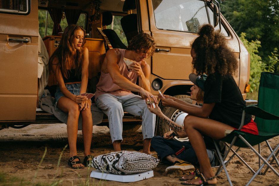 A group of friends enjoying a camping trip with a camper van, embodying diversity and fun in the outdoors.
