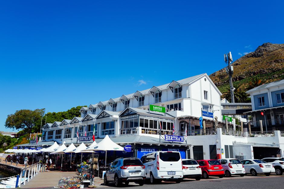 Lively outdoor shopping with stores and cars in sunny Cape Town, perfect for travel content.
