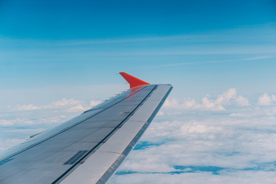 Aerial view from plane showcasing airplane wing above fluffy clouds and blue sky.