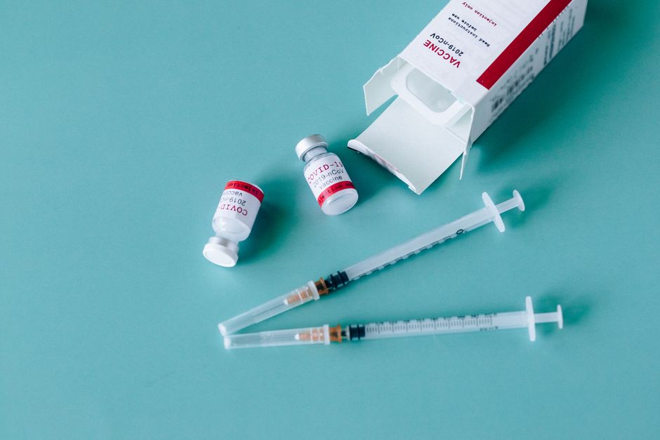 Close-up of COVID-19 vaccine vials and syringes on a blue surface, symbolizing vaccination efforts.