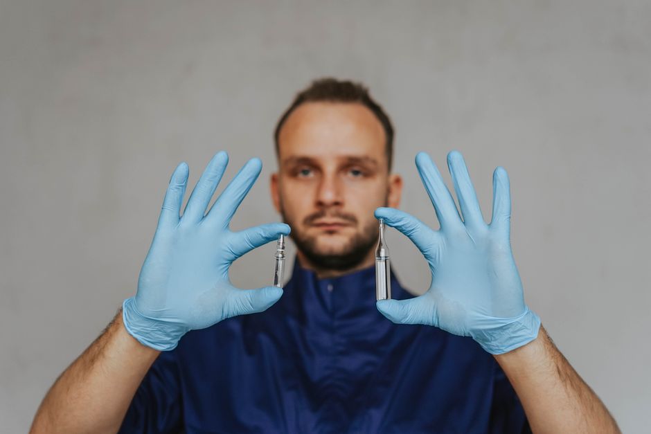 A healthcare professional wearing gloves holds ampoules with vaccines, focusing on medical safety.