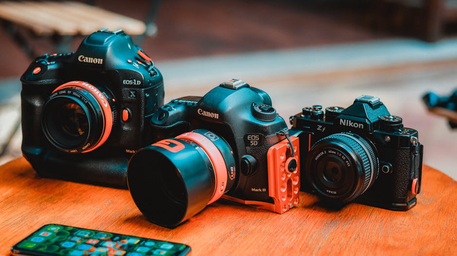 A collection of professional Canon and Nikon cameras displayed on a wooden table.